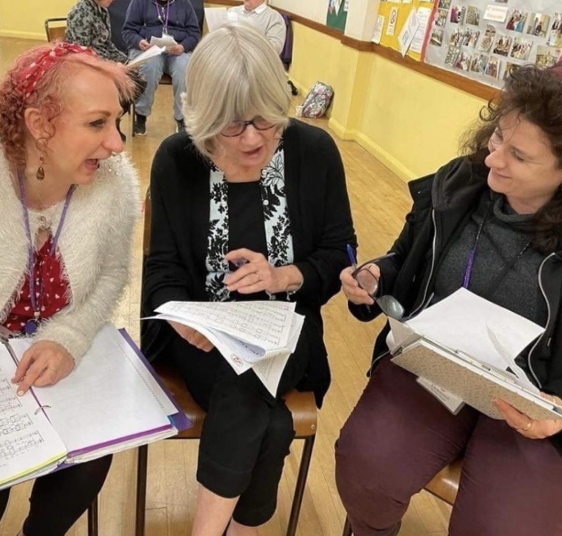 Members of More Harmony looking at sheet music together